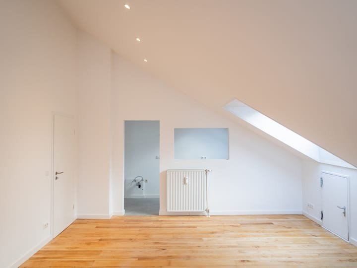 Sanierter Wohnraum unter dem Dach mit Holzboden und Dachfenster