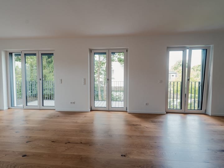 Heller Wohnraum mit drei bodentiefen Fenstern und Holzboden